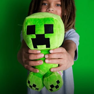 A kid holding up a creeper plush