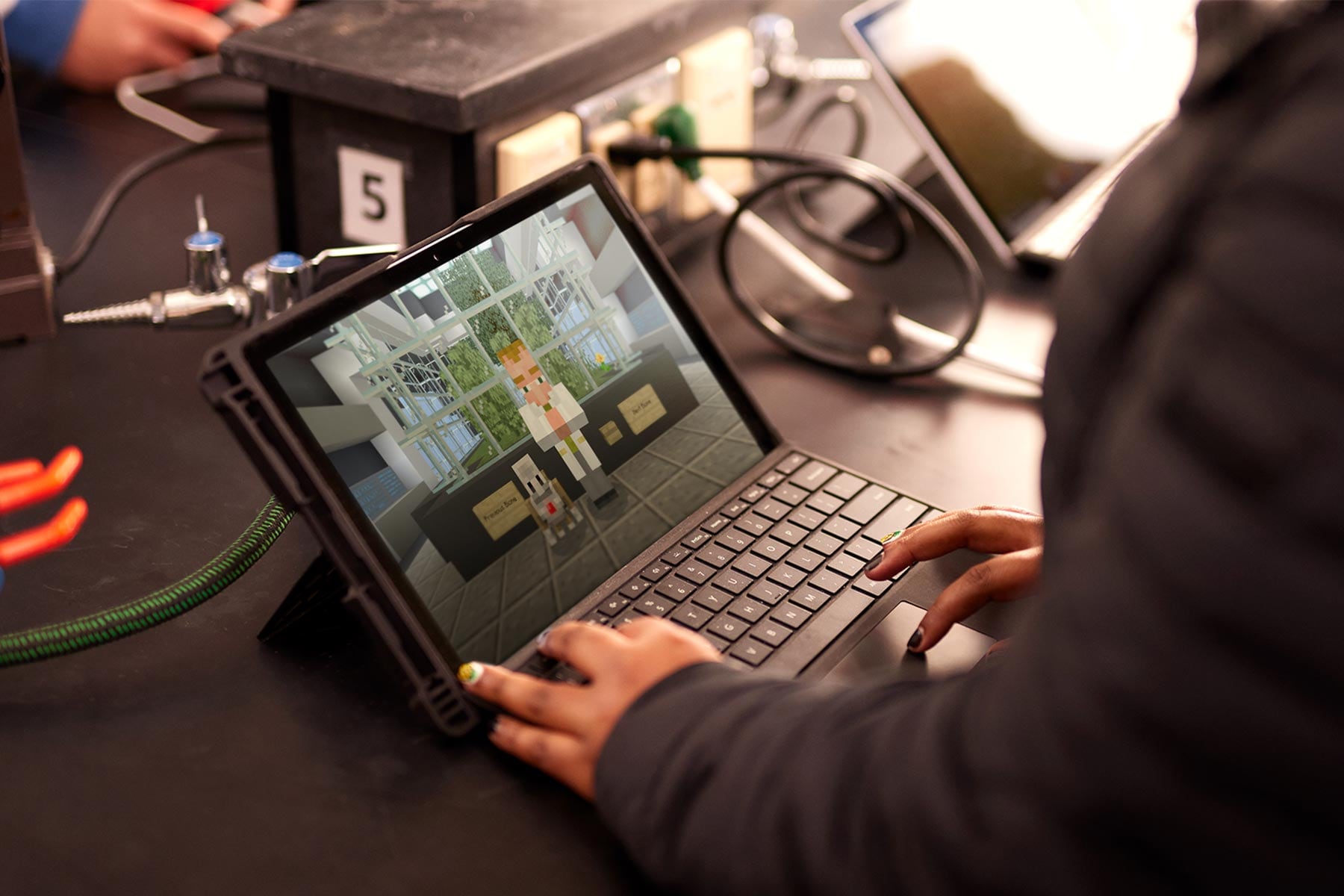 A student in a computer lab uses a laptop to take a Minecraft Education lesson.