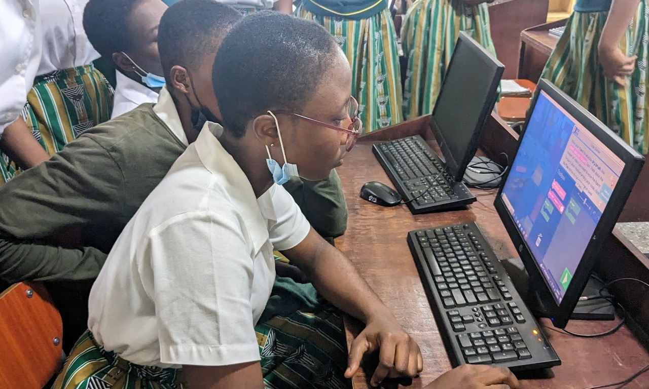 Several African students wearing school uniforms use Minecraft Education on desktop computers